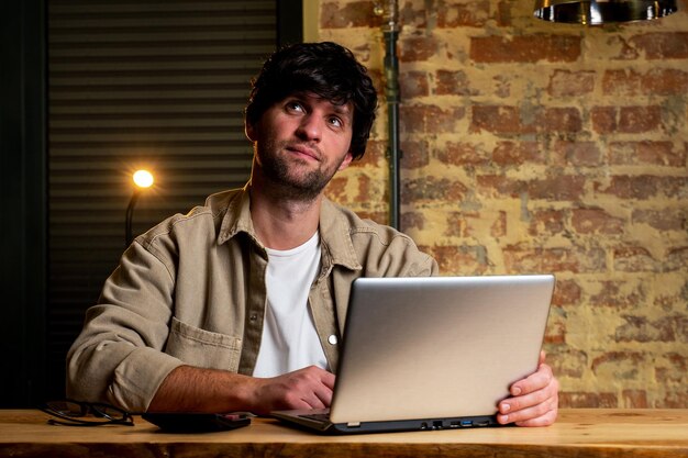 Retrato de um homem sonhador sentado em uma mesa trabalhando em um laptop pensando em resolver um problema um funcionário do sexo masculino pensativo pensando em uma ideia olhando para a tela do computador