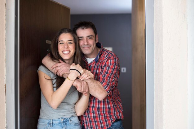 Foto retrato de um homem sorridente abraçando uma mulher enquanto está de pé contra a porta