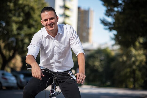 Retrato de um homem sorridente andando de bicicleta na estrada da cidade
