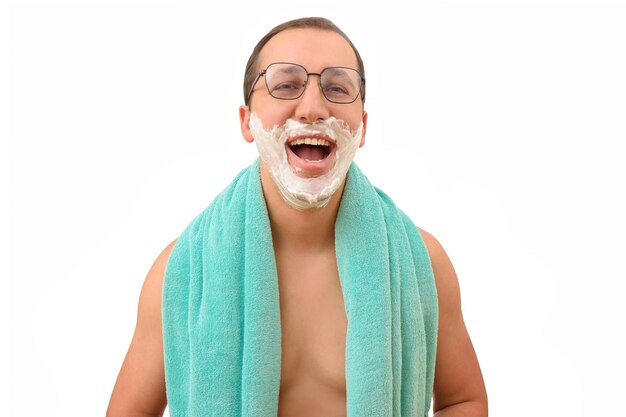 Retrato de um homem sorridente com espuma de barbear no rosto e uma toalha sobre um fundo branco