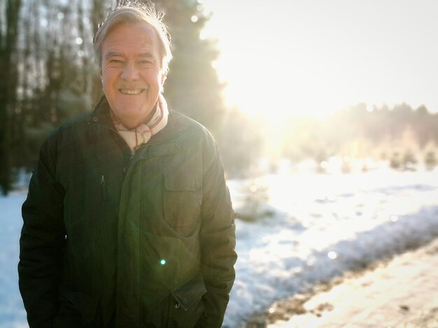 Retrato de um homem sorridente de pé em um campo coberto de neve