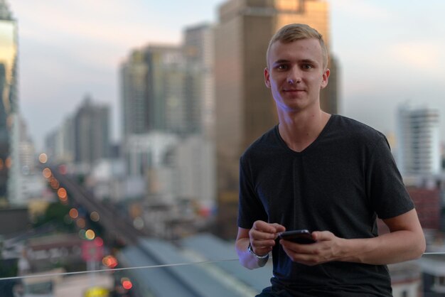 Foto retrato de um homem sorridente de pé junto a edifícios na cidade