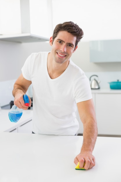 Retrato de um homem sorridente limpando balcão de cozinha