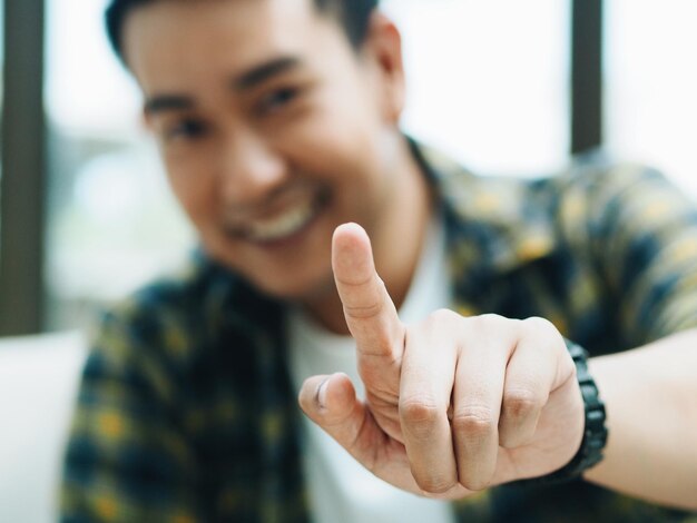 Foto retrato de um homem sorridente mostrando o dedo indicador