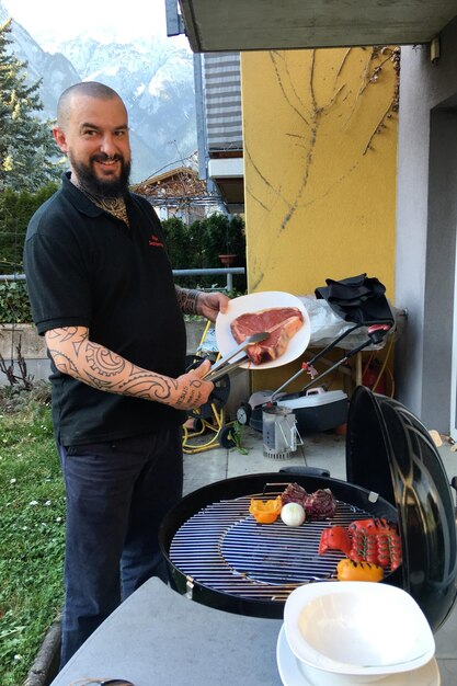 Foto retrato de um homem sorridente preparando comida em uma grelha de churrasco