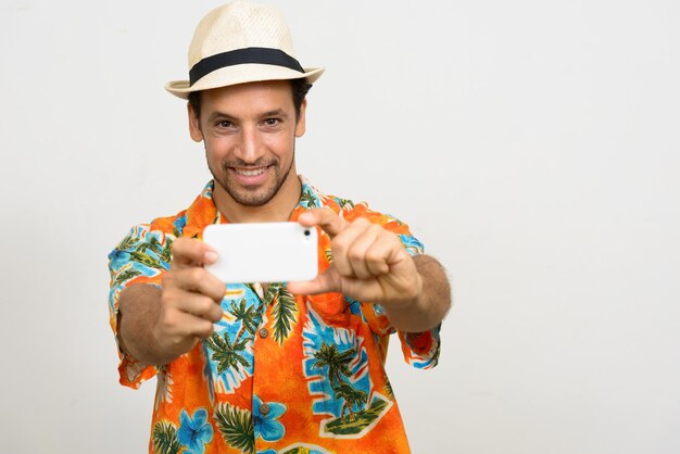 Foto retrato de um homem sorridente segurando uma câmera enquanto está de pé contra um fundo branco