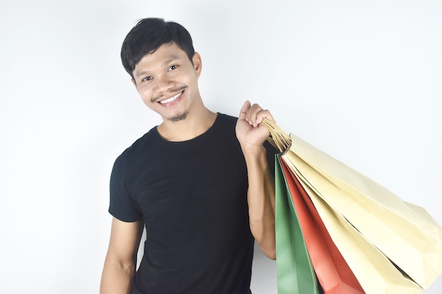 Retrato de um homem sorridente segurando uma sacola de compras em fundo cinza