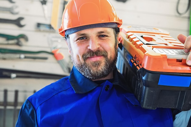 Retrato de um homem sorridente usando capacete e carregando uma caixa de ferramentas