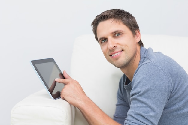 Retrato de um homem sorridente usando tablet digital na sala de estar