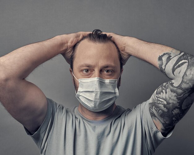 Foto retrato de um homem usando máscara de proteção contra um fundo cinzento