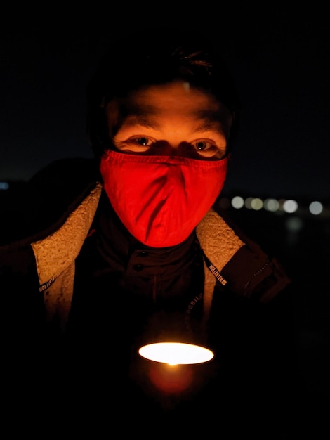 Foto retrato de um homem usando máscara segurando uma lanterna no escuro