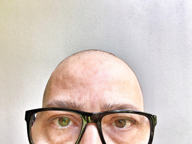 Retrato de um homem usando óculos contra a parede