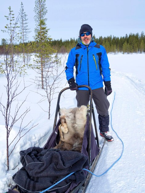 Foto retrato de um homem vestindo roupas quentes segurando um trenó na neve