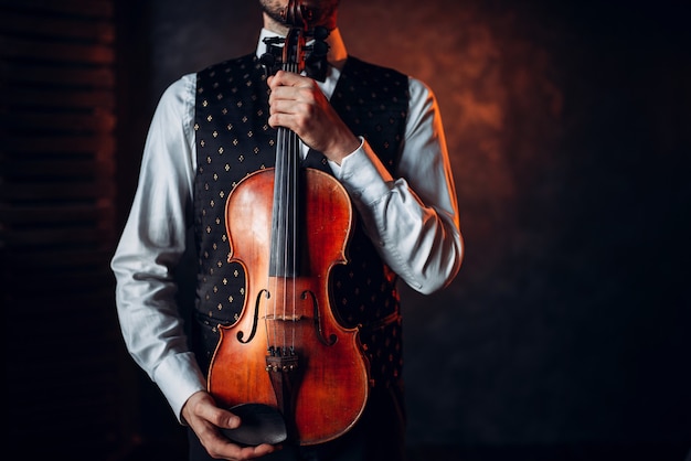 Retrato de um indivíduo do sexo masculino segurando um violino de madeira. Violinista com instrumento musical