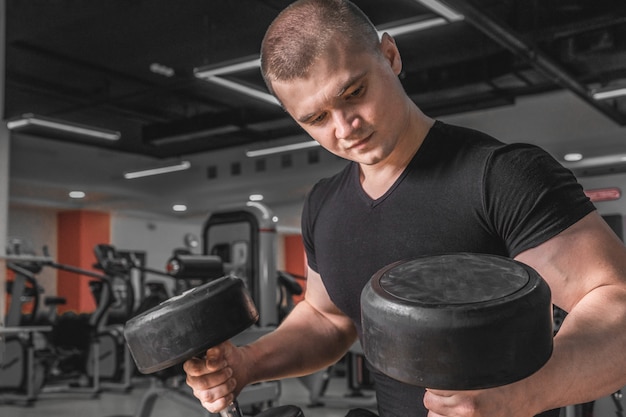 Retrato de um instrutor de fitness muscular com close-up de halteres.