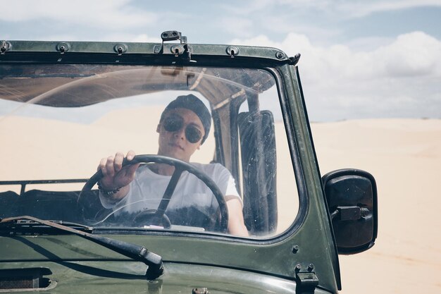 Foto retrato de um jovem a conduzir um carro no deserto