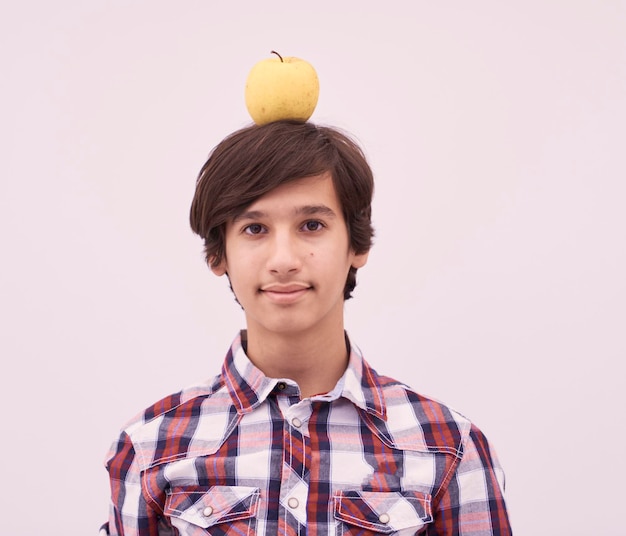 retrato de um jovem adolescente árabe com uma maçã na cabeça como alvo isolado no fundo branco