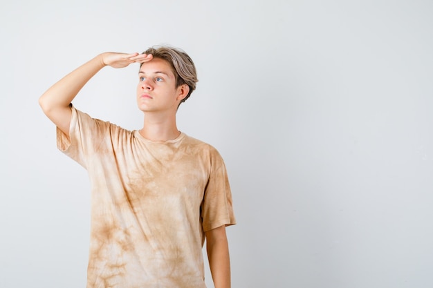 Retrato de um jovem adolescente olhando para longe com as mãos na cabeça em uma camiseta e olhando para a frente com foco