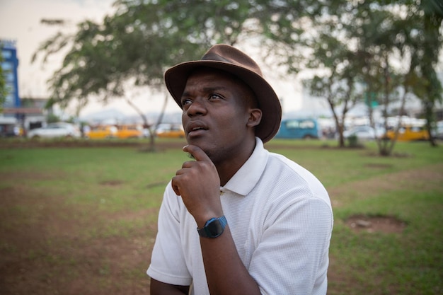 Retrato de um jovem adulto africano com uma expressão pensativa em um parque público