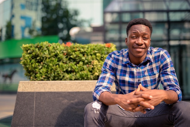 Retrato de um jovem africano bonito no parque ao ar livre da cidade