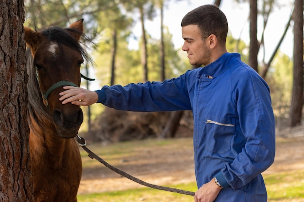 Retrato de um jovem agricultor acariciando seu cavalo