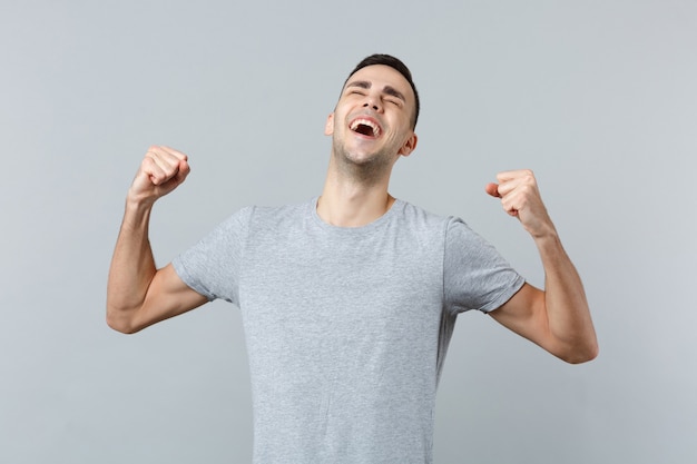 Retrato de um jovem alegre e feliz rindo em roupas casuais cerrando os punhos como vencedor