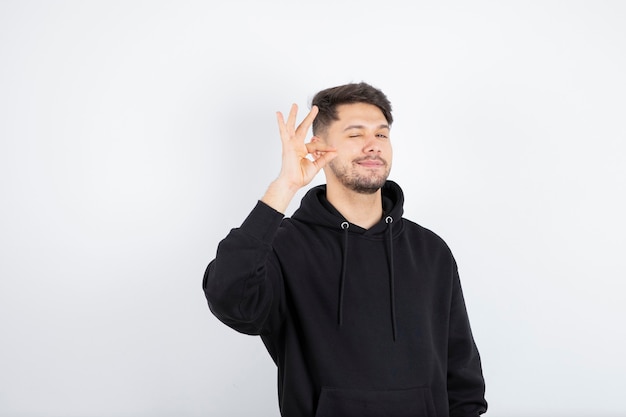 Retrato de um jovem alegre, mostrando um gesto de aprovação isolado no fundo branco