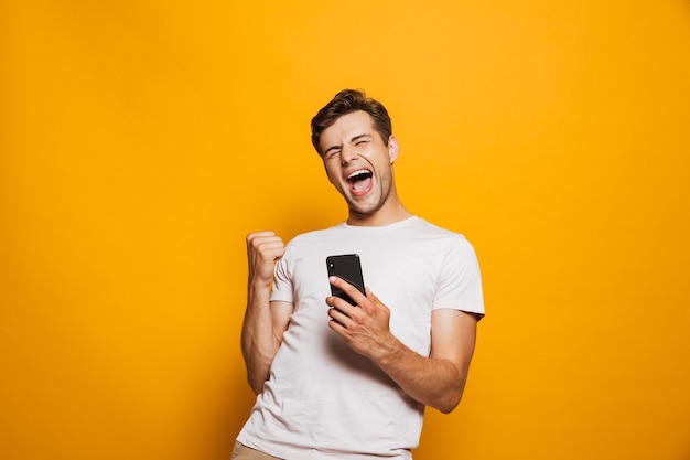 Foto retrato de um jovem alegre segurando um telefone celular