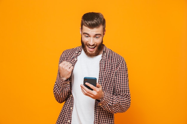 Retrato de um jovem alegre, vestindo roupas casuais, usando telefone celular