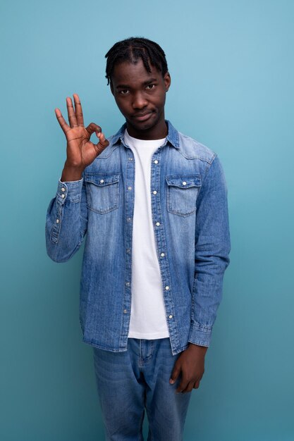 Retrato de um jovem americano alegre com dreadlocks em uma jaqueta jeans mostrando que tudo