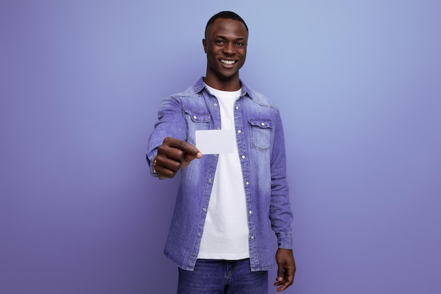 Retrato de um jovem americano bem preparado, com roupas jeans, segurando um cartão plástico pago com