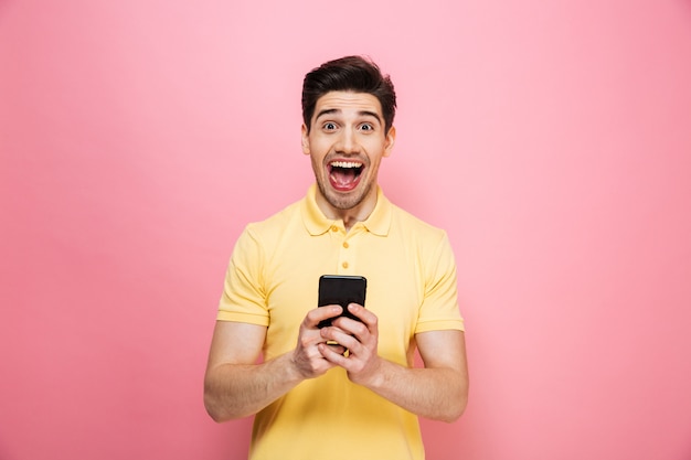 Retrato de um jovem animado, segurando o telefone móvel