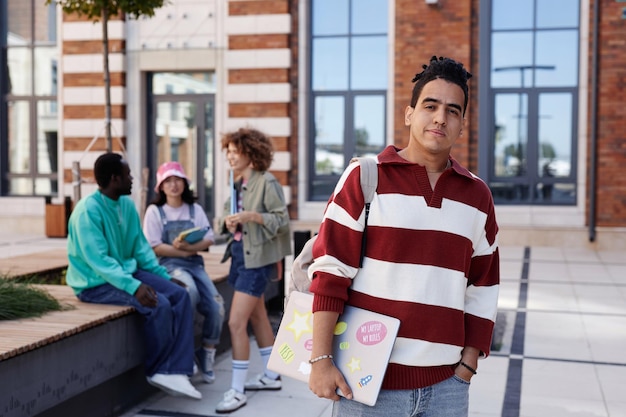 Retrato de um jovem árabe como estudante do sexo masculino sorridente de pé ao ar livre no campus da faculdade sorrindo no espaço de cópia da câmera