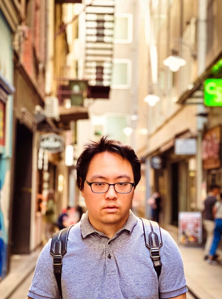 Foto retrato de um jovem asiático de óculos de pé na rua da cidade