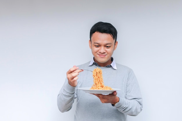 Retrato de um jovem asiático feliz gosta de macarrão comendo o conceito de almoço