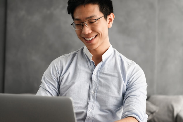 Retrato de um jovem asiático feliz usando computador portátil