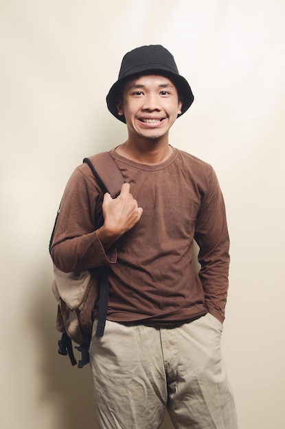 Retrato de um jovem asiático sorridente carregando mochila pronta para viajar isolada no fundo