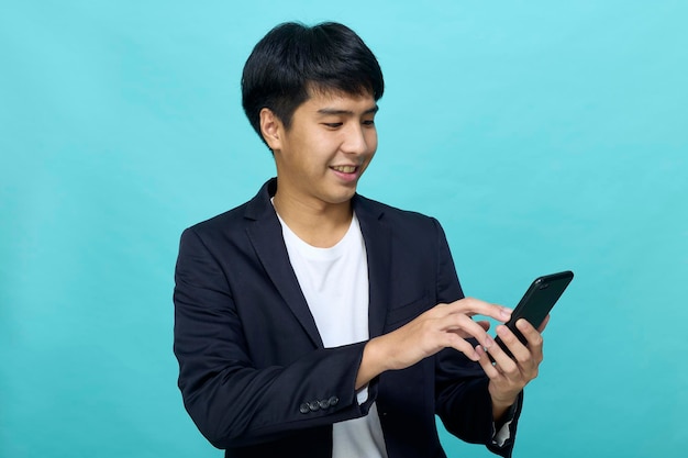 Retrato de um jovem asiático sorridente e bonito em um terno semiformal usando um telefone celular