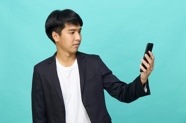 Retrato de um jovem asiático sorridente e bonito em um terno semiformal usando um telefone celular