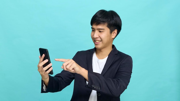 Retrato de um jovem asiático sorridente e bonito em um terno semiformal usando um telefone celular