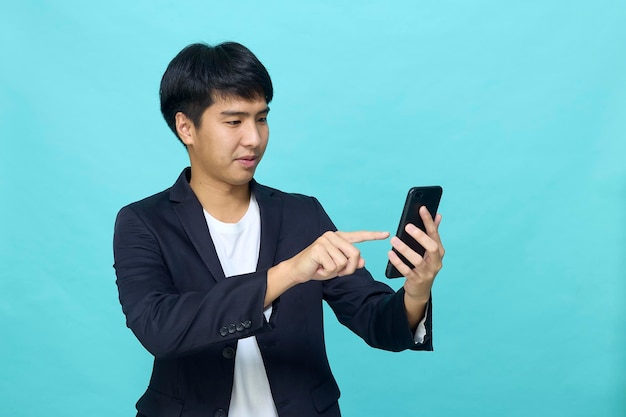 Retrato de um jovem asiático sorridente e bonito em um terno semiformal usando um telefone celular