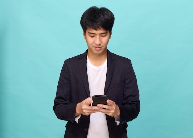 Retrato de um jovem asiático sorridente e bonito em um terno semiformal usando um telefone celular