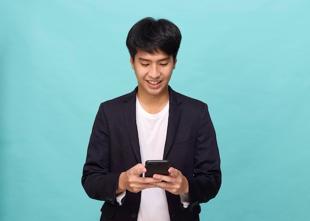 Retrato de um jovem asiático sorridente e bonito em um terno semiformal usando um telefone celular