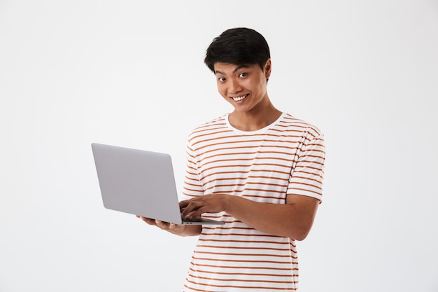 Retrato de um jovem asiático sorridente usando um laptop