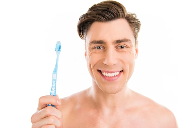 Retrato de um jovem atraente e alegre segurando uma escova de dentes