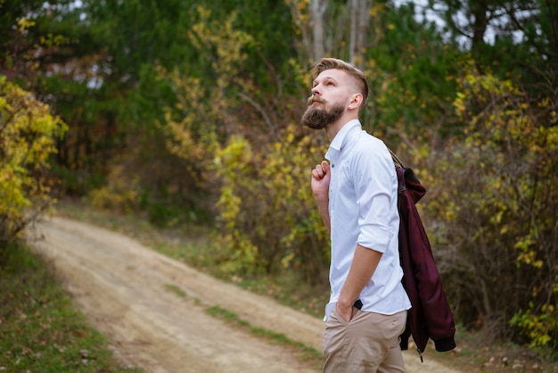 Retrato de um jovem barbudo caminhando na estrada no parque no outono bonito homem caucasiano em
