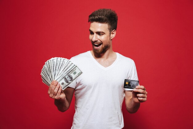 Retrato de um jovem barbudo feliz segurando dinheiro