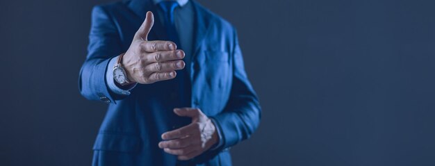 Retrato de um jovem bonitinho alegre bem-sucedido apresentando novo produto mostrando espaço de cópia na palma da mão em fundo cinza