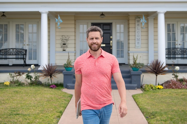 Retrato de um jovem bonito andando do lado de fora da nova casa Agente imobiliário bem sucedido comprando casa para fins de investimento