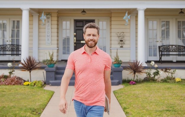 Retrato de um jovem bonito andando do lado de fora da nova casa agente imobiliário bem sucedido comprando casa